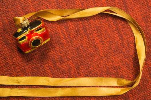 Christmas tree decoration on textile background. Christmas tree toy in a form of a camera. copy space