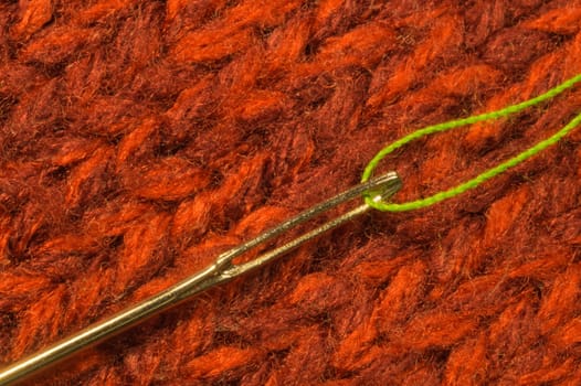 Needle with thread on red textile background. macro view