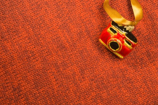 Christmas tree decoration on textile background. Christmas tree toy in a form of a camera. copy space