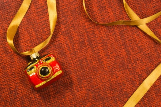 Christmas tree decoration on textile background. Christmas tree toy in a form of a camera. copy space