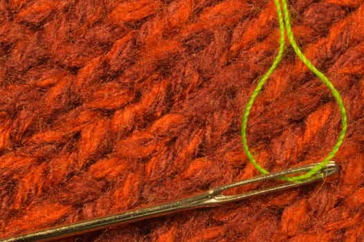 Needle with thread on red textile background. macro view