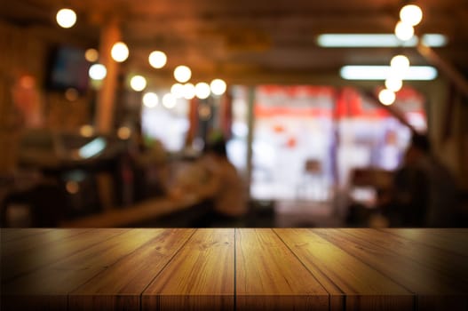 Empty wooden table top with blurred coffee shop or restaurant interior background. Abstract background can be used for display or montage your products.