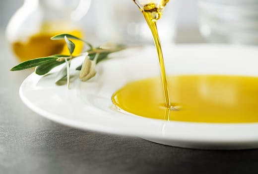 Bottle of healthy virgin olive oil pouring to plate close up. Healthy background concept