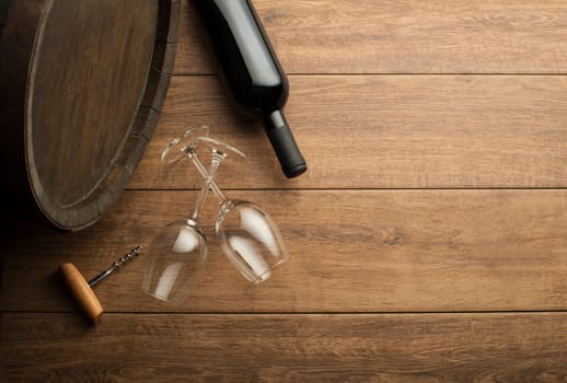 Bottle of red wine on old board. Wine bottle and glass with barrel background