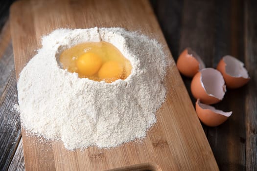 Two eggs in flour with egg shells on the side.