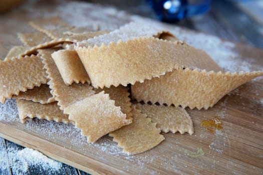 Fresh cut homemade pappardelle pasta on wooden board.