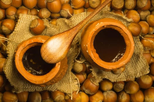 Honey pot with wooden spoon and nuts background