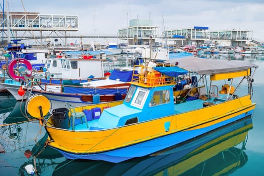 Colorful fishing boats moored in Limassol marina with restaurants on pier, Cyprus