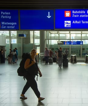 FRANKFURT AM MAIN, GERMANY - AUGUST 29, 2018: People with luggage exiting Frankfurt airport, Info board with direction signs above, Frankfurt am Main, Germany