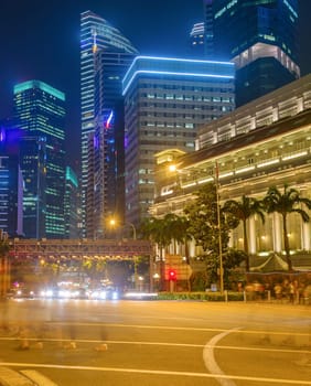 Singapore metropolis, Downtown core illuminated in night, crowd of people in motion blur crossing city highway, buildings of modern architecture in background