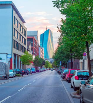 Downtown street cityscape with cars parking and European Central Bank modern building in evening sunlight, Frankfurt am Main, Germany