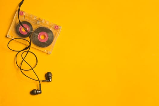 Earphones and retro cassette on yellow background. copy space