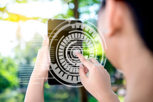 Rear view of business woman touch a circle in virtual screen on the digital tablet which display the interface of world map and binary code on the park. Digital technology concept