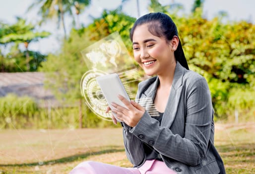 Beautiful asian business woman using digital tablet on her hand with virtual screen which display the interface of world map and binary code on the park. Digital technology concept