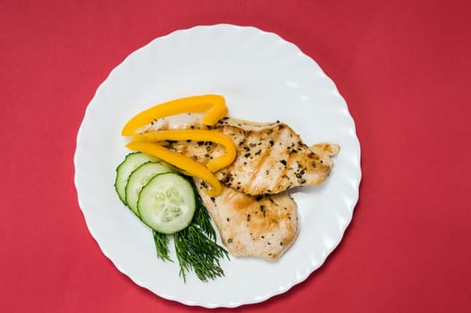 grilled chicken fillet on a white plate and red background