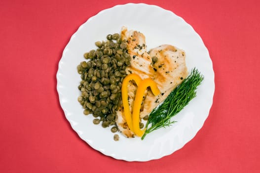 grilled chicken fillet with lentils on a white plate and red background