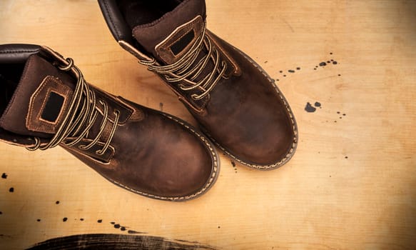 Men's brown boots on stone gravel background. Closeup isolated