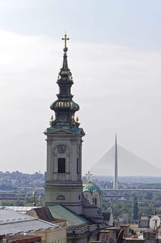 Church tower and new Ada bridge pylon in Belgrade Serbia