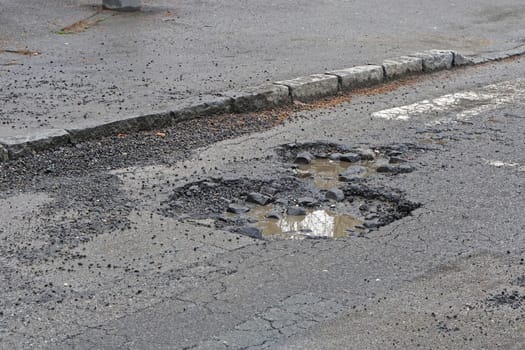 Very big pot hole filled with water at street