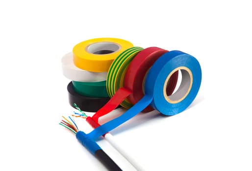 Rolls of insulation tape of different colors with the cable on white background. Blurred concept