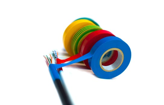 Rolls of insulation tape of different colors with the cable on white background. Blurred concept