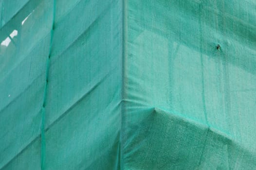 Under construction building covered with green debris netting.