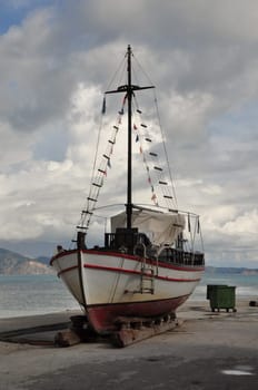 Old wooden fishing boat on shore for repair.