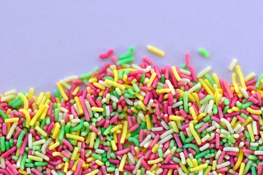 Colorful candy sprinkles garnish sweet food topping on white background.