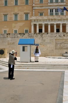 ATHENS, GREECE - JUNE 9, 2014: Tourist taking photos of the greek parliament and evzone soldier with traditional uniform guarding the tomb of the unknown soldier.