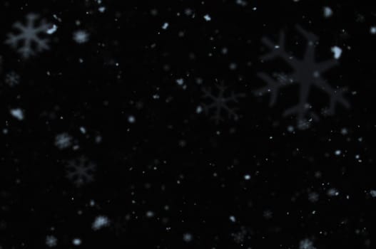 Snow falling on cold winter night. Snowflakes bokeh blur effect abstract background.