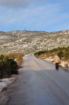 ATHENS, GREECE - JANUARY 4, 2015: Man walking on Penteli mountain in Athens, Greece. Snow melting on sunny winter day.