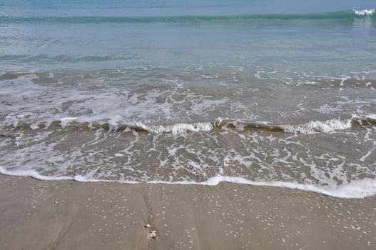 Waves crashing on sandy beach. Waters edge abstract sea background.