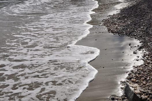 Waves crashing on stone beach. Waters edge abstract sea background.