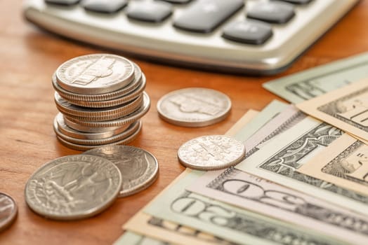 Coin stack with dollar bills and a calculator