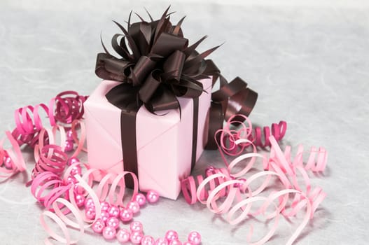Gift pink box with ribbons, beads and a brown bow