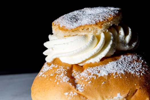 Swedish Lenten Bun (Semla) Close up with black background.