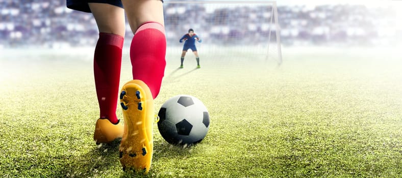 Football player woman in orange jersey kicking the ball in the penalty box on football field