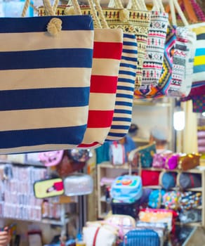 Grand Bazaar market in Tehran, rows of colorful textile crafts shops, bags in foreground, Iran