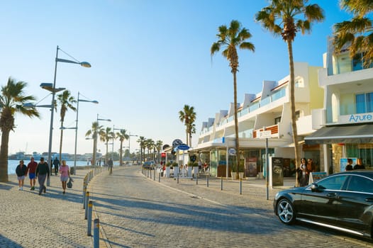 PAPHOS, CYRPUS - FEBRUARY 13, 2019: People walking by Cyprus promenade at sunset. Paphos - famous tourist destination in Cyprus
