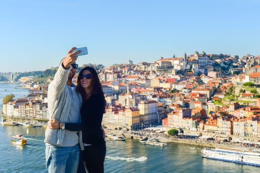 PORTO, PORTUGAL - Couple taking selfie in front of Old Town of Porto, Portugal
