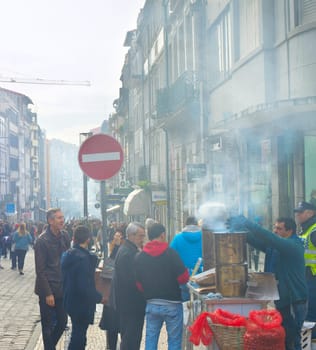 PORTO, PORTUGAL - NOVEMBER 11, 2016: Local seller selling chestnut on Santa Catarina street - main shopping street of Porto, Portugal