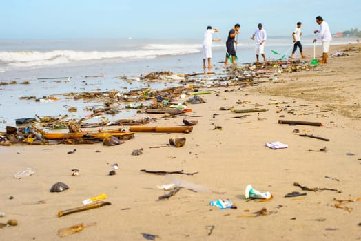 Group of people cleaning up the beach from the garbage and plastic waste. Bali island, Indonesia