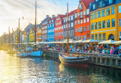 Nyhavn view with boats by embankment at sunset, people, motion blur, Copenhagen, Denmark