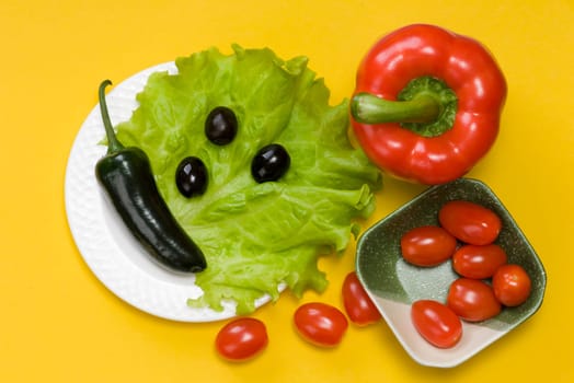 still life of jalapeno pepper,  bell pepper, tomato cherry, lettuce on yellow background