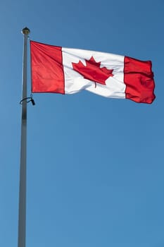 The Canadian Flag on a Falgpole with a clear blue sky.