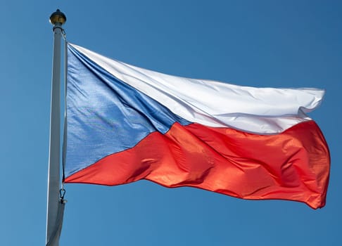 Flag of the Czech Republic close up with a clear blue sky.