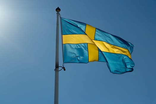 The Flag of Sweden Close Up waving in the wind with a clear blue sky.