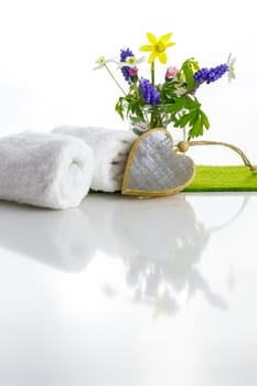 White towels with heart on a white background with flowers in a vase. Spring.