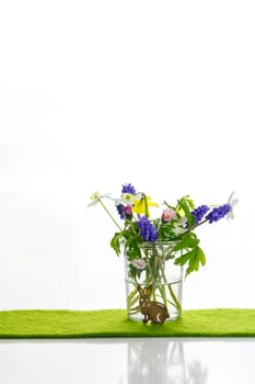 White towels next to a cream tin against a white background and flowers in a vase. Spring. Easter bunny.