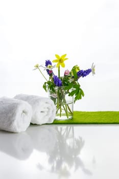 White towels with heart on a white background with flowers in a vase. Spring.